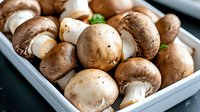 Fresh whole brown and white mushrooms in gray container with green basil leaves, macro food photography for cooking, restaurant menu and healthy eating.