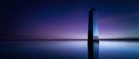 Minimalist monolith structure reflected in still water at twilight with purple and blue gradient sky, suitable for modern design and conceptual projects.