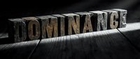 Wooden letterpress blocks spelling DOMINANCE on dark wooden surface with dramatic lighting for business and leadership concepts.