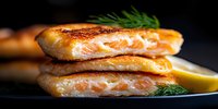 Grilled salmon fillet with crispy golden crust cut in half showing juicy pink center, garnished with fresh dill and lemon on dark plate, panoramic food shot.