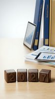 Wooden blocks spelling 2027 on desk with business reports and charts in background for planning and forecasting concepts.