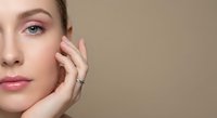Young Caucasian woman with natural makeup touching face gently, skincare and beauty concept for cosmetic products and wellness treatments.