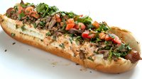 Gourmet hot dog topped with fresh salsa, chopped herbs, and savory meat on a toasted bun, perfect for food service menus and recipe illustrations.