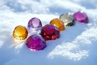 Colorful gemstones and crystals scattered on fresh white snow with sunlight creating magical sparkles and reflections, winter jewelry photography concept.