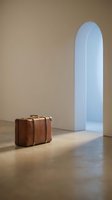 Vintage leather suitcase in minimalist interior with arched doorway and warm natural lighting for travel and lifestyle concepts.
