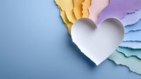 White paper heart on colorful torn paper background with copy space for romantic designs, greeting cards, and love-themed projects.