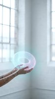 Hand holding holographic torus shape with digital wireframe pattern in modern office space with natural window lighting for futuristic technology concepts.