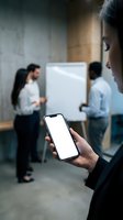 Business professional holding smartphone with blank white screen during office meeting presentation for mobile app mockup and digital communication.