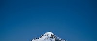Snow-covered mountain peak against clear blue sky, suitable for travel, nature, and landscape design projects.
