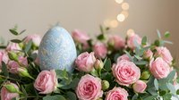 Easter egg with floral pattern nestled among pink roses and greenery with warm bokeh lights creating festive spring holiday decoration atmosphere.