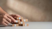 Businessman hands arranging wooden blocks with lightbulb icons representing creative ideas, innovation strategy and problem-solving in corporate environment.