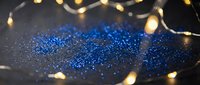 Blue glitter sparkles with warm golden fairy lights creating magical bokeh effect for festive celebrations and holiday decorations.