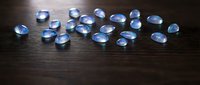 Clear blue glass marbles scattered on dark wooden surface creating elegant minimalist composition for gaming and decoration concepts.