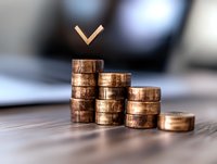 Descending stacks of copper coins with downward arrow symbol above, showing financial decline concept on blurred background. For business and economy themes.