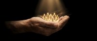 Mature male hand holding glowing golden human figures against dark background, symbolizing leadership, teamwork, success, and business growth opportunities.
