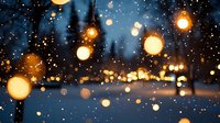Winter evening cityscape with warm glowing lights and falling snow creating magical bokeh effect against blurred urban background during snowfall.