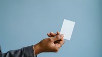 Man with dark skin tone holding blank white card against blue background for business messaging and promotional content.