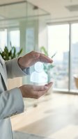 Businesswoman hands protecting glowing human figure icon in modern office representing employee care, HR management and workplace safety concepts.