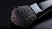 Professional makeup brush with soft bristles for cosmetic application and beauty routine on dark background for skincare and glamour concepts.