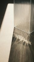 Sunlight filtering through vertical ribbed glass creates geometric shadows and light patterns on neutral wall surface, ideal for backgrounds and design projects.