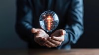 Businessman in blue shirt holding glowing crystal ball with illuminated circuit pattern inside, representing technology, innovation, future vision, and digital transformation for business concepts.
