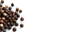 Scattered black peppercorns on white background, mix of whole dried black and white pepper seeds, macro food photography for culinary and spice designs.