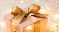 Elegant gift box with golden ribbon bow on sparkling bokeh background for holidays, celebrations, birthdays, Christmas, anniversaries and special occasions.