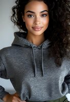 Young African American woman with natural curly hair wearing casual gray hoodie smiling at camera against light background, modern lifestyle portrait.