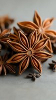 Star anise spices with whole cloves on neutral background for culinary cooking baking and seasoning applications in kitchen recipes and food preparation.