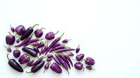 Fresh purple eggplants and chili peppers scattered on white background. Organic vegetables for healthy cooking and Mediterranean cuisine recipes.