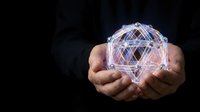 Hands holding glowing geometric crystal structure with sacred geometry patterns. Digital hologram sphere with interconnected lines for spiritual and technology concepts.