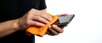 Male hand cleaning smartphone screen with orange microfiber cloth, isolated on white background for tech care and device maintenance concepts.