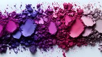 Crushed makeup eyeshadow and powder palette swatches in gradient from purple to pink shades on white background, creative cosmetics flatlay composition.
