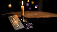 Mystical tarot cards with burning candle and amethyst crystals on dark wooden table creating atmospheric fortune telling scene for spiritual guidance.