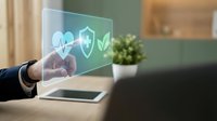 Healthcare protection and security concept with hand touching holographic display showing heart, shield and checkmark icons for medical insurance and wellness services.