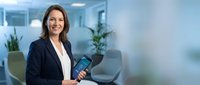 Professional businesswoman holding tablet in modern office environment with plants and natural lighting for corporate presentations.
