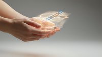 Hands holding transparent digital tablet with glowing holographic interface displaying data visualization and network connections for technology and innovation concepts.
