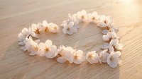 White flower lei arranged in heart shape on wooden surface with warm lighting for romantic wedding decoration concepts.