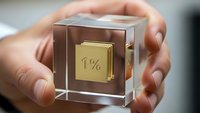 Hands holding transparent acrylic cube with golden one percent symbol inside representing exclusive membership and luxury status concept.