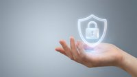 Caucasian hand holding glowing security shield with padlock icon, representing data protection, cybersecurity, and digital safety solutions for business and technology.