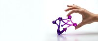 Hand holding purple molecular structure model on white background, representing science, chemistry, research, and education concepts.