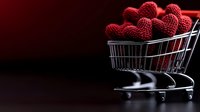 Red glittery hearts in shopping cart against dark background, romantic concept for Valentine's Day shopping and love-themed marketing campaigns.