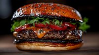 Juicy beef burger with melted cheese, fresh vegetables and black sesame bun on wooden surface, close up view of gourmet hamburger with glossy brioche.