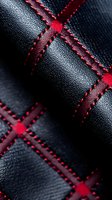 Luxury black leather texture with red cross-stitched diamond pattern detail, featuring precise quilted seams and contrasting thread in automotive upholstery style.