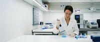 Female scientist in white lab coat conducting research with test tubes and laboratory equipment in modern medical facility for scientific studies.