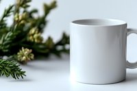 White ceramic coffee mug mockup with evergreen branch decoration on white background. Clean minimal product photography for branding and design presentation.