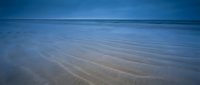 Serene ocean waves gently washing over sandy beach shore creating peaceful ripple patterns under blue sky for relaxation and meditation concepts.