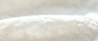 Soft beige linen fabric texture with natural fibers and gentle folds creating organic waves and shadows for textile design and home decor projects.