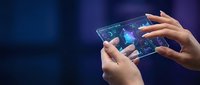 Hands holding transparent futuristic tablet with holographic interface displaying digital data analytics and glowing elements on dark blue background.