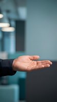 Open palm of a Caucasian male professional in business attire gesturing offering, presenting, or receiving concept in modern office environment.